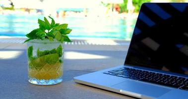 una foto di un laptop e un cocktail a bordo piscina