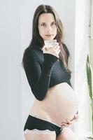 donna incinta che beve caffè foto