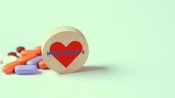 icona del cuore su blocco di legno posto davanti alla pillola, foto