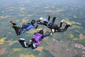 quattro paracadutisti in caduta libera tenendosi per mano
