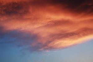 drammatico paesaggio al tramonto con nuvole gonfie illuminate dal sole al tramonto arancione e dal cielo blu. foto