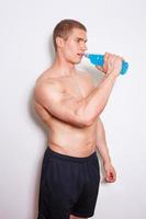giovane uomo muscoloso senza camicia che beve di nuovo una bevanda energetica