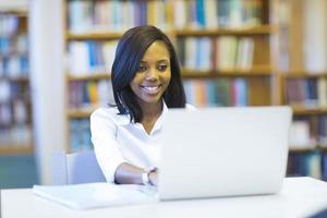 studente di college afroamericano femminile che per mezzo del computer portatile foto
