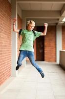 salto maschio felice dello studente del liceo foto