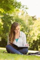 studente universitario sorridente seduto e scrivere sul blocco note foto