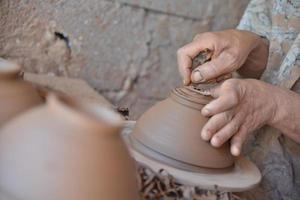 artigiano marocchino lancia una pentola di terracotta su un tornio da vasaio.