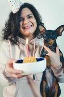 ragazza felice che dà una torta fatta in casa al suo cane, al chiuso foto