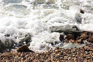bella immagine di sfondo di ciottoli sulla spiaggia con onde e mare. foto