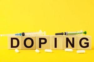 doping, il testo è scritto su cubetti di legno su fondo giallo e siringhe mediche. foto