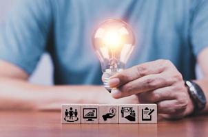 la mano toccò anche la lampadina sul blocco di legno. processo aziendale nuove idee innovative e stimolanti tecnologia innovativa nel concetto di lavoro di un uomo d'affari deve avere una buona idea. foto