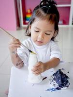bambina divertirsi a dipingere sulla bambola di stucco foto