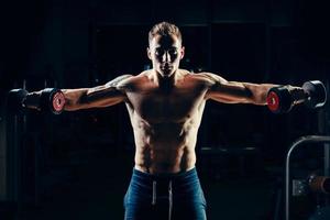 bodybuilder muscolare atleta allenamento indietro con manubri in palestra foto