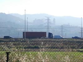 traffico in autostrada e tralicci dell'alta tensione sullo sfondo foto