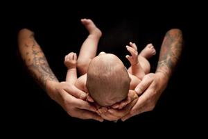 le mani del padre e della madre tengono il neonato sul nero