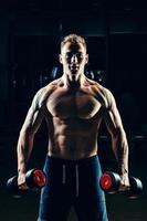 bodybuilder muscolare atleta allenamento indietro con manubri in palestra foto