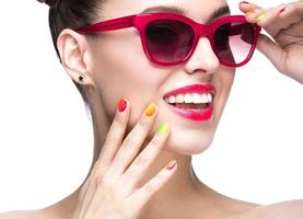 ragazza in occhiali da sole rossi con trucco luminoso e unghie colorate.