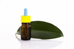 bottiglia di olio essenziale di vetro ambrato vuota con pipetta su sfondo di foglie verdi. copia spazio foto