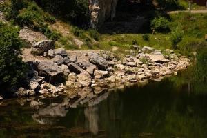 vista della costa di un lago di montagna in primo piano con grandi pietre e riflesso nell'acqua. scenario. foto