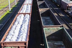 vagoni di carbone e fertilizzanti minerali in grandi pacchi come parte di un treno. foto