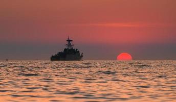 silhouette nave da guerra militare e il sole. foto