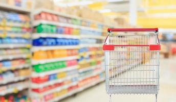 corridoio del supermercato sfondo sfocato con carrello rosso vuoto foto