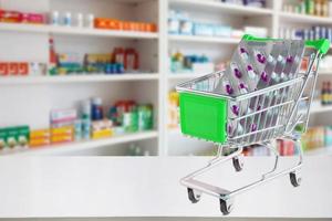 capsule di pillole medicinali nel carrello sul bancone della farmacia con sfocatura sullo sfondo sfocato degli scaffali della farmacia foto