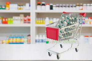 capsule di pillole medicinali nel carrello sul bancone della farmacia con sfocatura sullo sfondo sfocato degli scaffali della farmacia foto