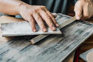 il falegname usa carta abrasiva per levigatura a secco per lucidare il legno in officina, creatore di fai da te e concetto di lavorazione del legno. messa a fuoco selettiva foto