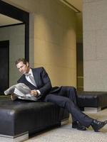 uomo d'affari rilassato leggendo il giornale nella hall dell'ufficio foto