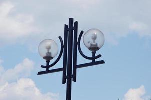 lampada rotonda stradale, illuminazione esterna della città contro il cielo blu e le nuvole. foto