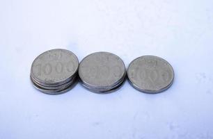 foto ravvicinata di 1000 monete rupie, valuta indonesiana ordinatamente disposte in 3 pile isolate su sfondo bianco