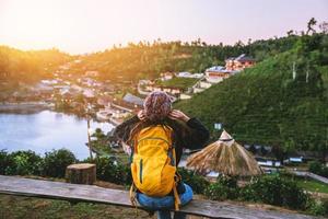 giovane donna con lo zaino che gode del tramonto sul picco della montagna. turisti in piedi in una piantagione di tè a guardare il bellissimo sole di montagna al villaggio tailandese di ban rak. foto