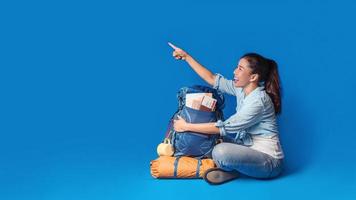 giovane viaggiatore asiatico donna felice in camicia blu con zaino con e attrezzatura per le vacanze dei viaggiatori con una mappa, su sfondo di colore blu. zaino da viaggio