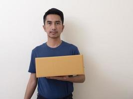 giovane in possesso di una scatola isolata su uno sfondo bianco foto