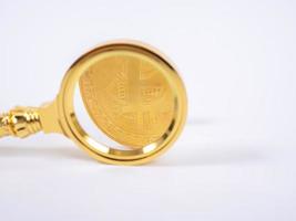 lente d'ingrandimento bitcoin dorata su uno sfondo sfocato di monete foto