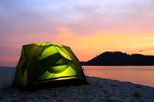 tenda verde sulla spiaggia al tramonto foto