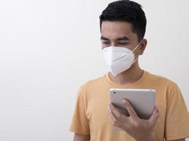 l'uomo con tavoletta digitale indossa una maschera chirurgica per proteggersi dal virus foto