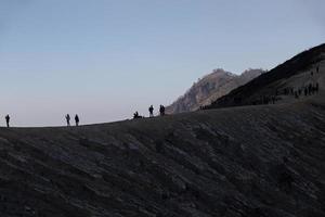 turisti escursionistici che si godono la vista dell'alba a java indonesia del monte ijen foto