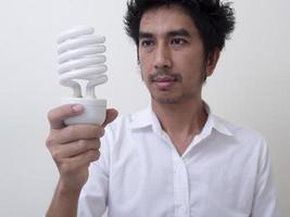 uomo che tiene lampadina a risparmio energetico per lampada foto