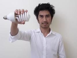 uomo che tiene lampadina a risparmio energetico per lampada foto
