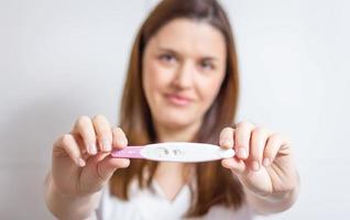 donna felice che mostra il suo test di gravidanza positivo foto