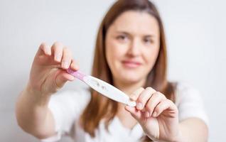 donna felice che mostra il suo test di gravidanza positivo foto