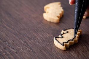 primo piano di decorare simpatici biscotti di pipistrello di Halloween con glassa. foto