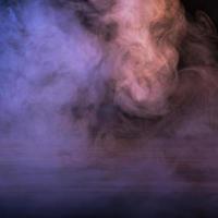 immagine concettuale di fumo multicolore isolato su sfondo nero scuro e tavolo in legno. foto