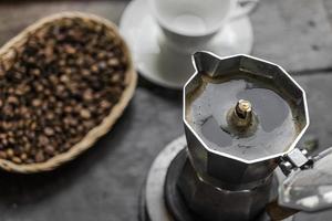 caffè espresso mattina fatto in casa nella moka sul tavolo di legno scuro. foto