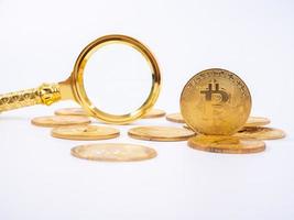 replica bitcoin dorato e lente d'ingrandimento su sfondo bianco concetto di affari e finanza. foto