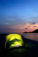 tenda verde sulla spiaggia al tramonto foto
