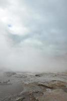 bei cieli nuvolosi con un geyser fumante in Islanda foto