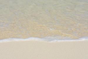 dolci onde che lambiscono la spiaggia di sabbia bianca foto