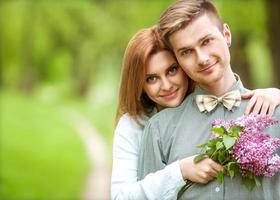 coppia in amore nel parco sorridendo in possesso di un mazzo di fiori